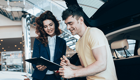 A car saleswoman explains features to a customer in a dealership, highlighting a positive interaction in a modern, well-lit automotive showroom.