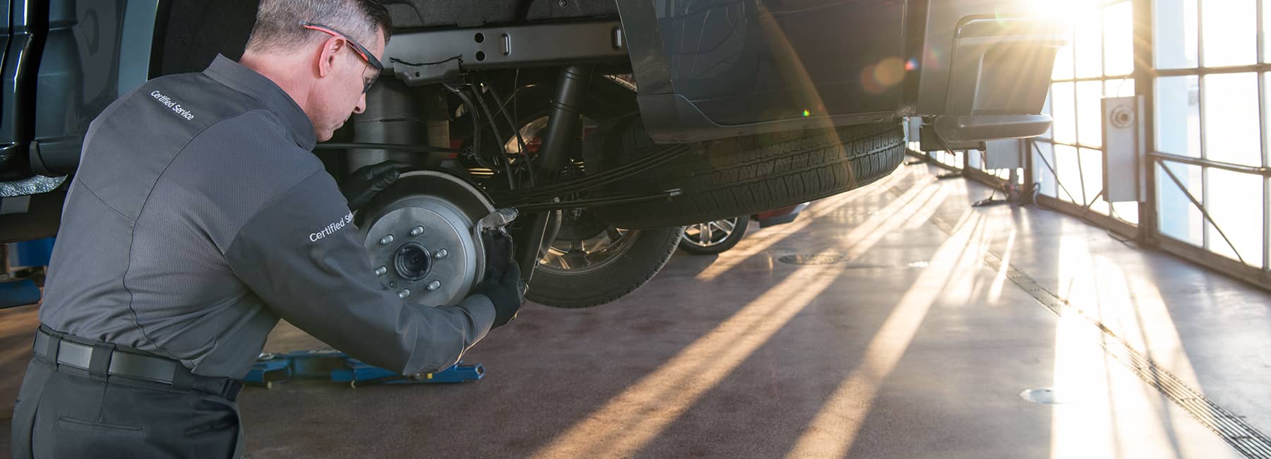 A mechanic performing brake maintenance on a vehicle in a well-lit garage, showcasing quality automotive service with a focus on precision and care.